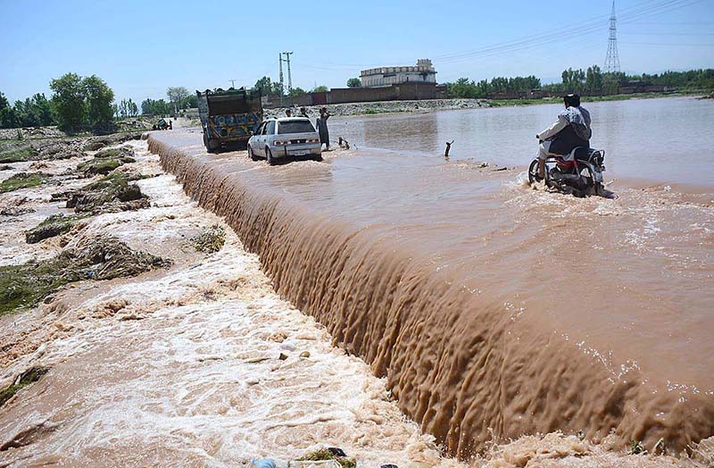 Vehicles passing through flood water at Bara Bazar Khuwani bridge after heavy rain in Provincial Capital.