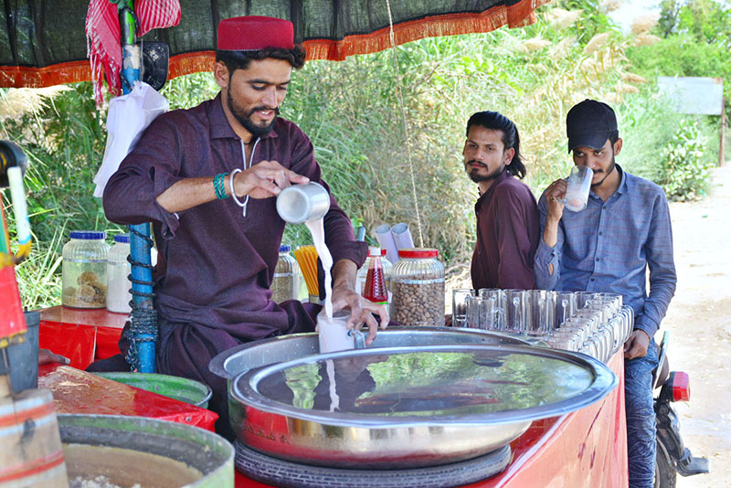 Vendor selling traditional drink Thadal to customers on the roadside during hot weather in the city.