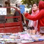 Women selecting old books from a roadside vehicle at Mall Road