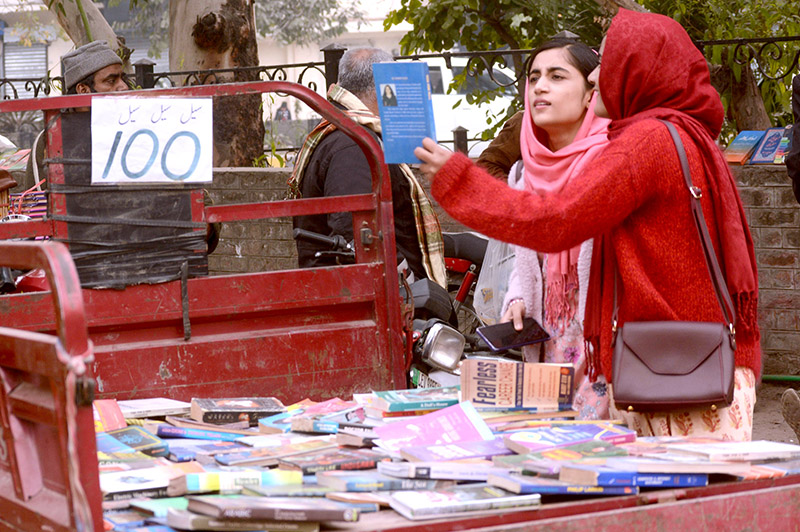 Women selecting old books from a roadside vehicle at Mall Road