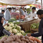 Customers purchasing vegetables at Sunday market in the city