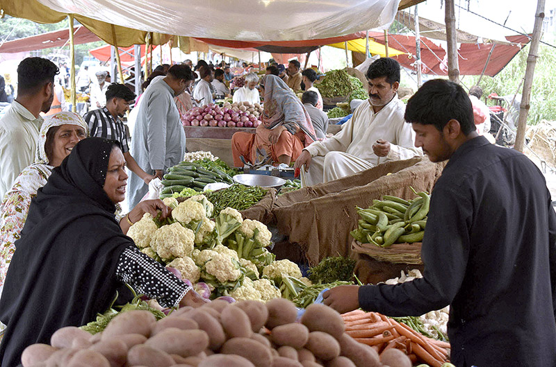 Customers purchasing vegetables at Sunday market in the city