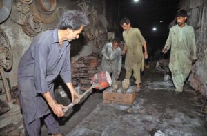 Workers filling melt trash iron into the structure to prepare different new spare parts in the iron molding factory.