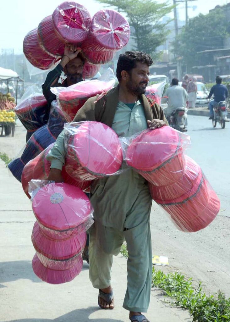 Street vendor on the way carrying straw made stools looking for customers in the city.