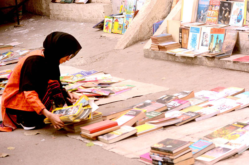 Women selecting old books from a roadside vehicle at Mall Road