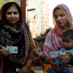 Women voters showing their national identity cards and marked thumbs after casting their votes during the by-election 2024 at Garhi Shahu School