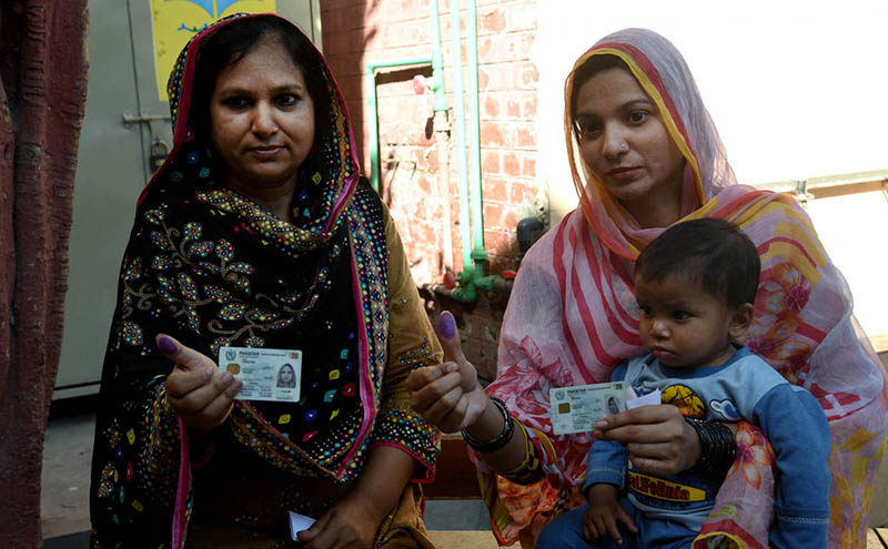 Women voters showing their national identity cards and marked thumbs after casting their votes during the by-election 2024 at Garhi Shahu School