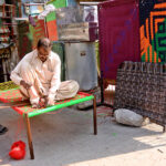 A skilled worker knitting traditional bed (Charpoi) at his workplace in the city