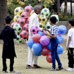 Children looking to buy balloons and footballs from a street hawker