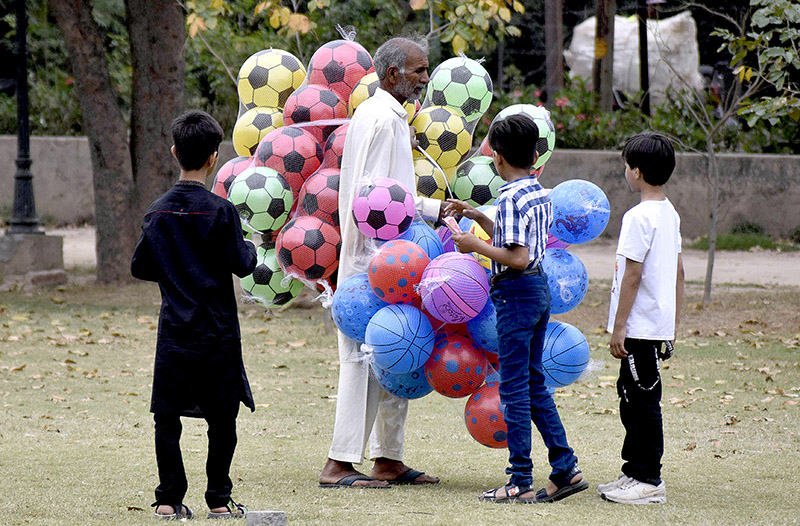 Children looking to buy balloons and footballs from a street hawker