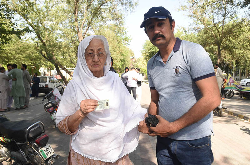 Women voters showing their national identity cards and marked thumbs after casting their votes during the by-election 2024 at Garhi Shahu School