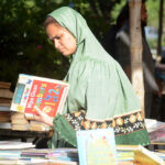 A woman selecting old books from book fair stall at Frere Hall.