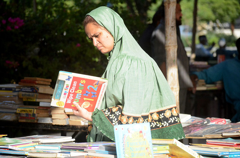 A woman selecting old books from book fair stall at Frere Hall.