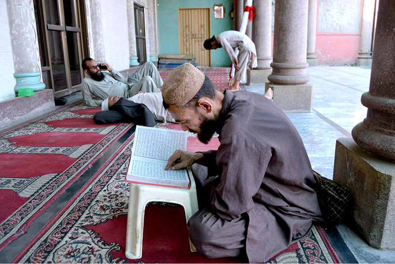 A person is engrossed in reciting the Holy Quran in Jamia Masjid Noori