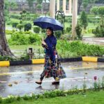 A woman on the way under cover an umbrella to protect herself from rain at Defence Road