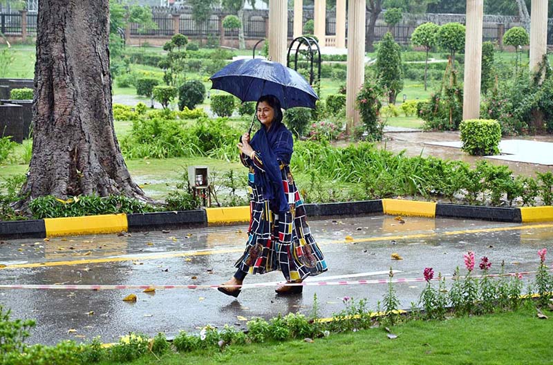 A woman on the way under cover an umbrella to protect herself from rain at Defence Road