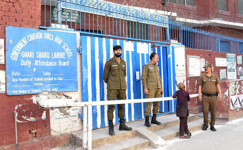 Police officials stand alert outside the polling station during the by-election 2024 at Barf Khana Chowk Railway Road.