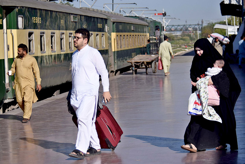 Passengers carry their luggage as they arrive at the railway station to depart for their hometowns to celebrate the Eid al-Fitr with their loved ones