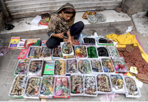 A vendor to put on bangles to a girl at Resham Gali during Eid shopping