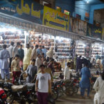 People selecting Peshawari sandals from vendor in preparation of upcoming Eid ul fitr at Bacha Khan Market