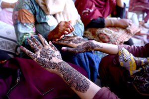 A beautician applies " Henna" design on customers' hands, ahead of Eid-ulFitr
