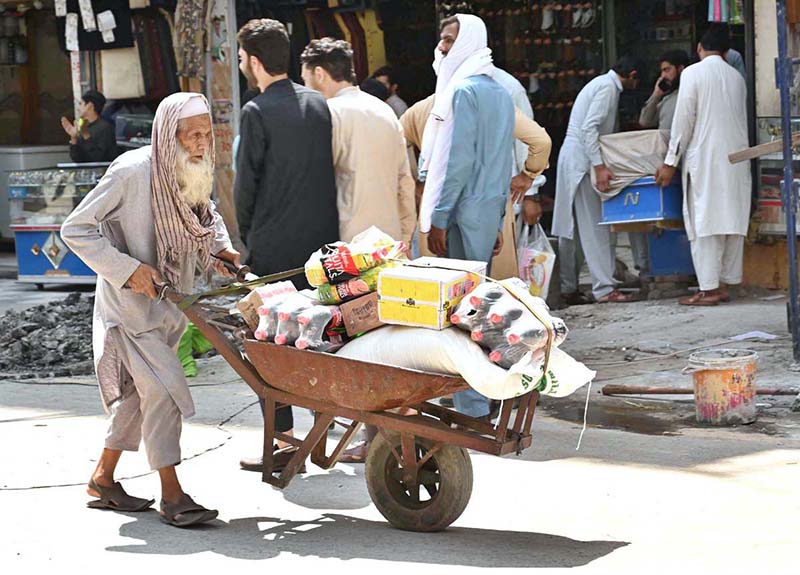 An aged person carrying cold drinks and other items on his handcart to supply at Qissa Khawani Bazar