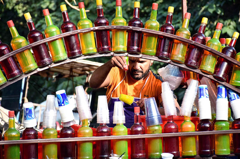 A vendor busy in preparing and selling the ice-lolly for customers on his hand cart setup outside the Sheranwala Gate.