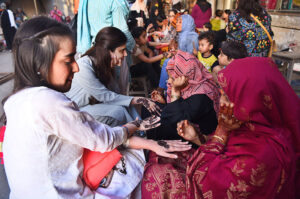 A beautician applies " Henna" design on customers' hands, ahead of Eid-ulFitr