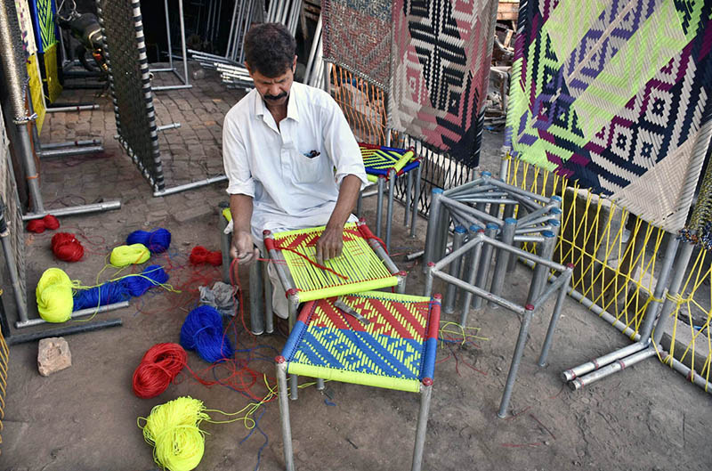 A worker busy in knitting the traditional stool and traditional bed (Charpai) for customers at his workplace