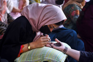 A beautician applies " Henna" design on customers' hands, ahead of Eid-ulFitr
