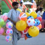 A vendor selling balloons in a local park.