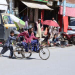 A boy helps a disabled person on wheelchair, crossing road at Meezan Chowk