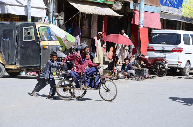 A boy helps a disabled person on wheelchair, crossing road at Meezan Chowk