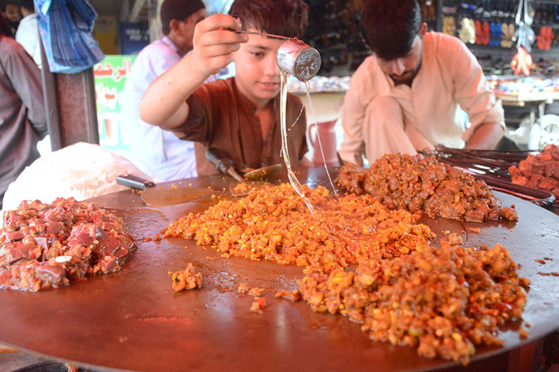 A young vendor preparing traditional food item for customers at Saddar