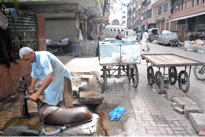 A person busy in filling “mashk” (container used for carrying or storing water) to deliver to residents of Saddar area.