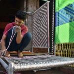 Skilled youngster knitting the traditional bed (Charpai) for sell at his workplace