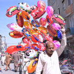 A vendor displays air filled toys to attract customers at Bara Bazar