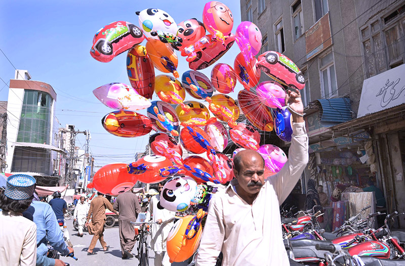 A vendor displays air filled toys to attract customers at Bara Bazar