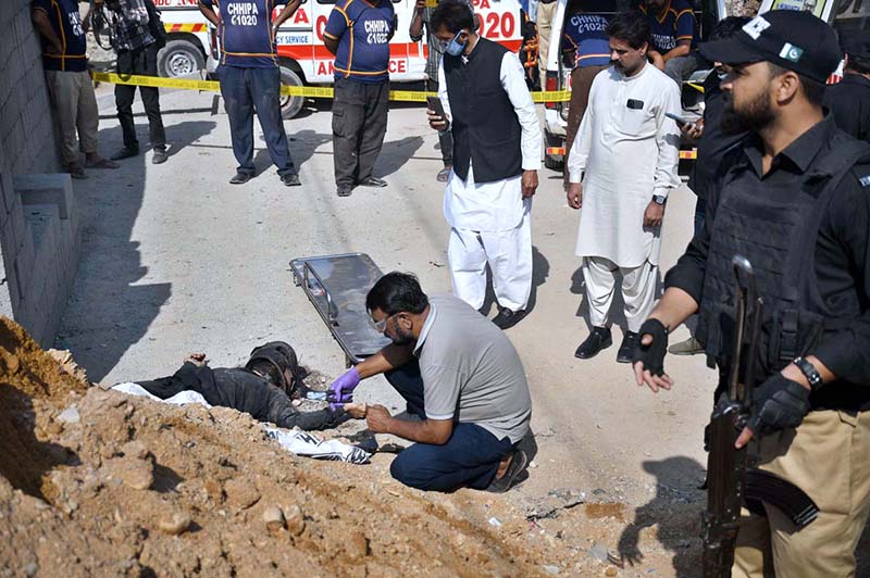 Police official inspect a dead body of a suspected attacker at the site of suicide attack on a convoy of foreign nationals in the Landhi area.