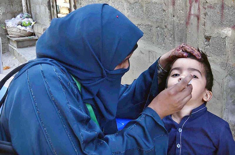 A lady health worker administering polio drops to a child.