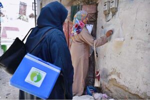 A lady health worker administering polio drops to a child.