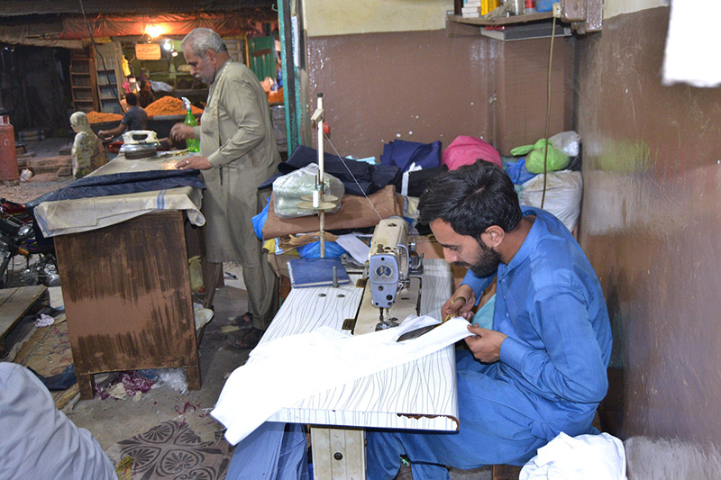 Tailors stitching clothes at his workplace Islampura as per increased flow of customers ahead of Eid Al-Fitr