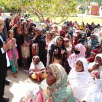 Dr. Muhammad Amjad Saqib, Chairperson of the Benazir Income Support Programme (BISP), interacts with a group of women beneficiaries who have come to receive their stipend at a payment campsite