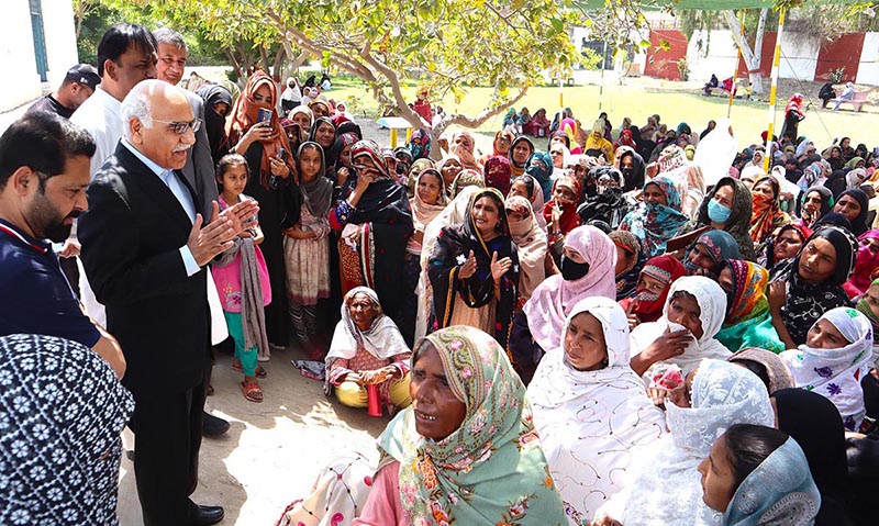 Dr. Muhammad Amjad Saqib, Chairperson of the Benazir Income Support Programme (BISP), interacts with a group of women beneficiaries who have come to receive their stipend at a payment campsite