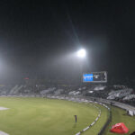 People sit under the cover of polythene sheet during rainfall before the start of the first Twenty20 International Cricket Match between Pakistan and New Zealand at the Rawalpindi Cricket Stadium