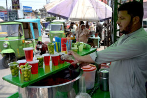A vendor selling traditional summer drink to attract customers during hot day in the city.