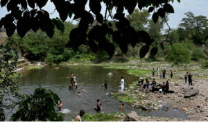 Youngsters enjoy bathing in the pond to get some relief from hot weather in the Federal Capital