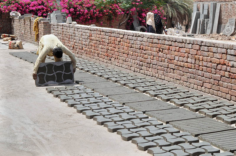worker is busy in making and spreading tuff tiles for drying at his workplace.