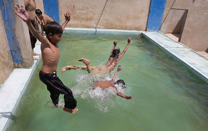 Youngsters jumping and bathing in the swimming pole to get relief from hot weather in the city.