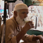 An elder man enjoy drinking traditional dirnk (Lassi) to get relief from hot weather in the city